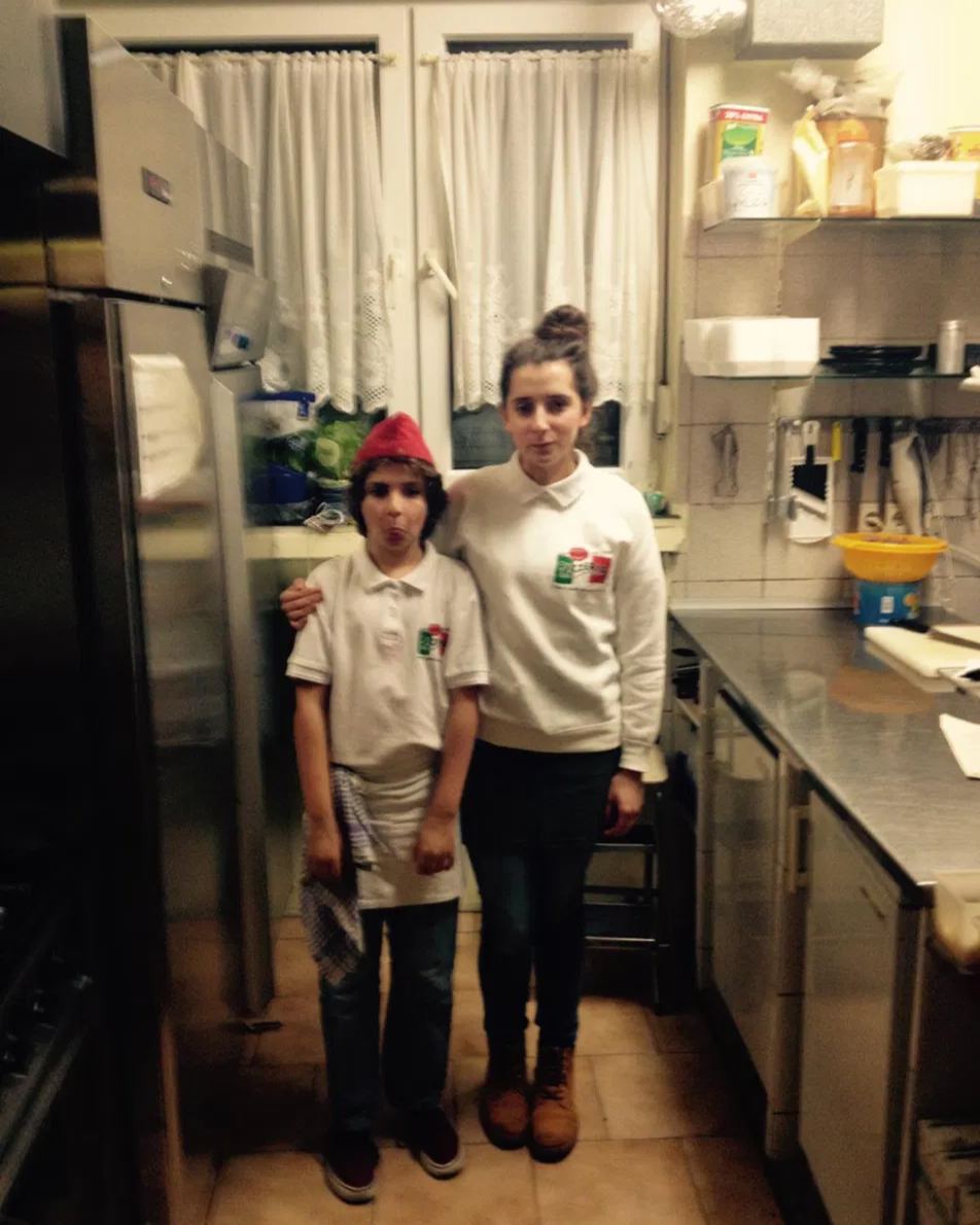 Dion und Dana als Kinder in Arbeitskleidung in der Küche der Pizzeria