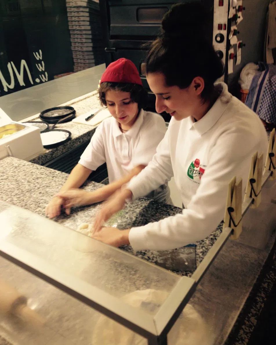 Dion und Dana als Kinder beim Teigkneten an der Theke der Familienpizzeria